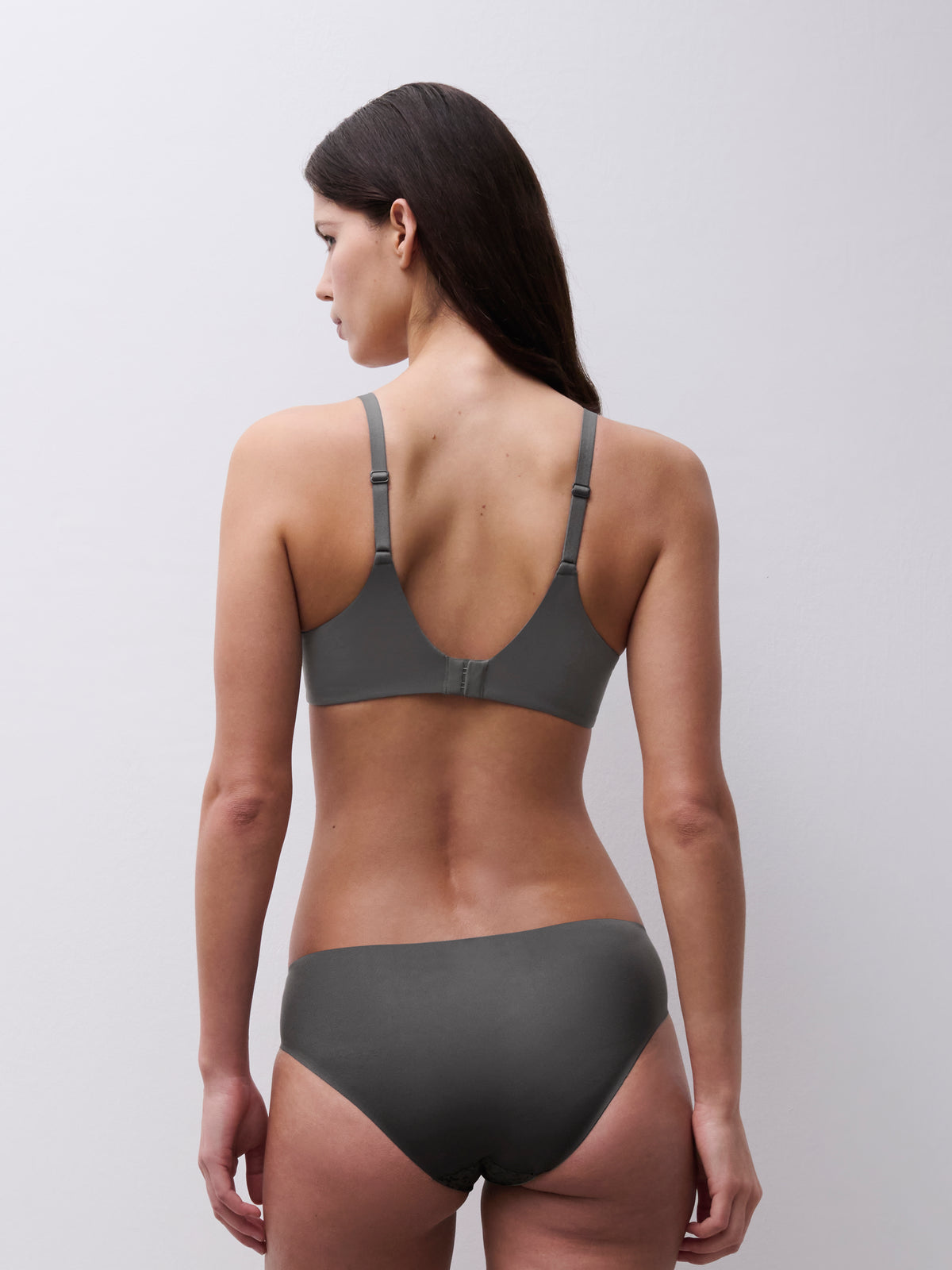 Woman wearing a gray bra and underwear set against a plain background
