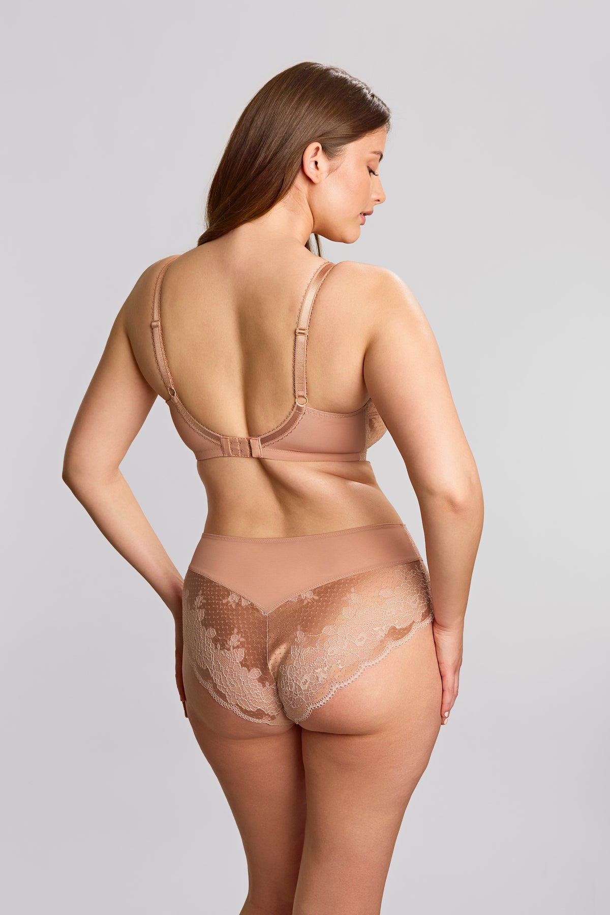 Woman wearing a beige shapewear bodysuit on a light gray background