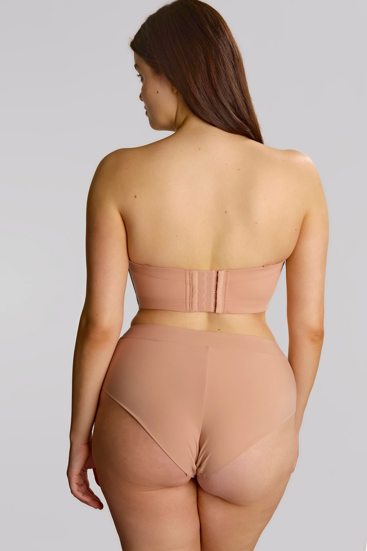 Woman wearing a beige shapewear outfit on a plain background
