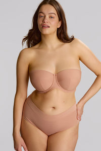 Woman wearing a beige strapless bra and panties set against a plain background