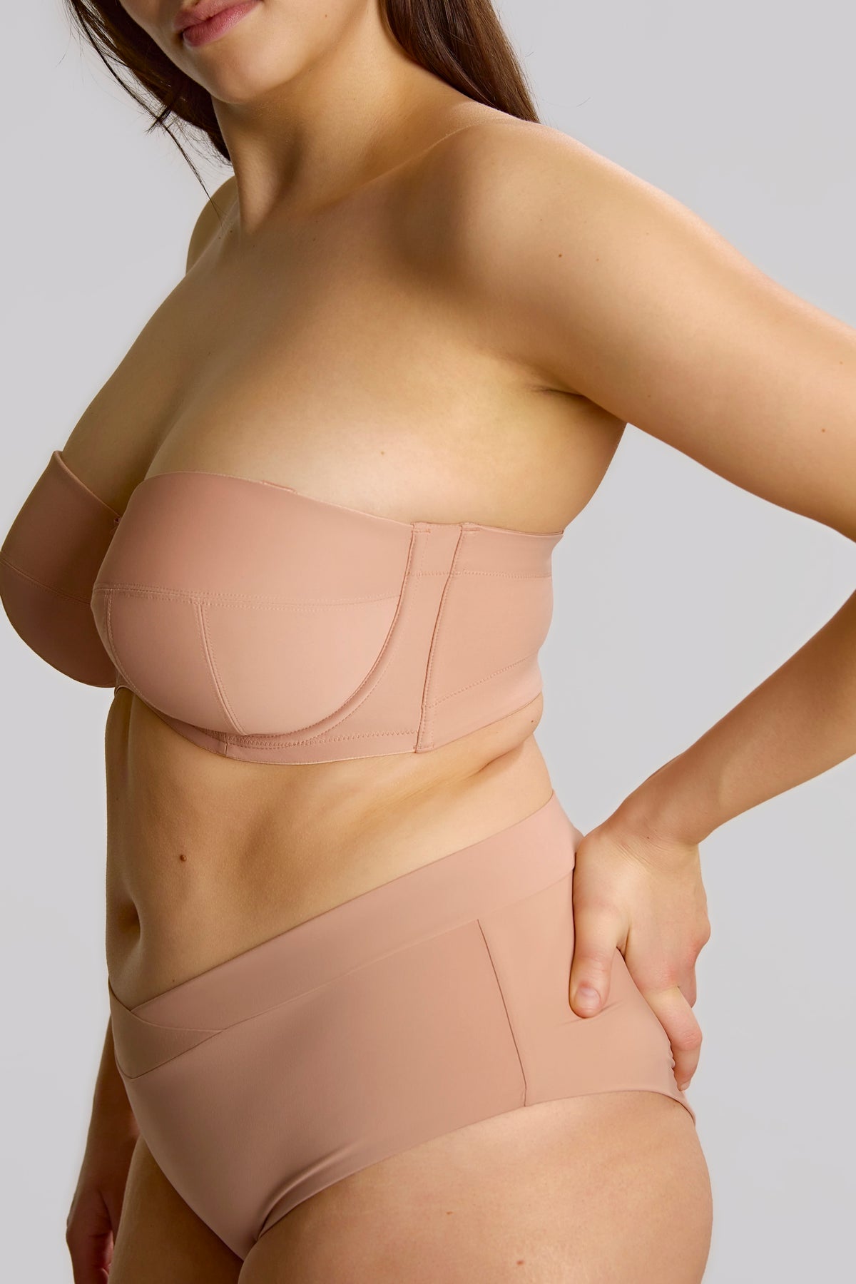 Woman wearing a beige shapewear garment on a plain background