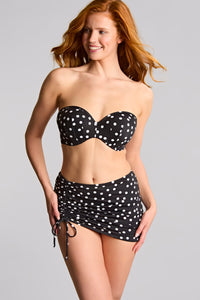 Woman wearing a black and white polka dot bikini set on a gray background