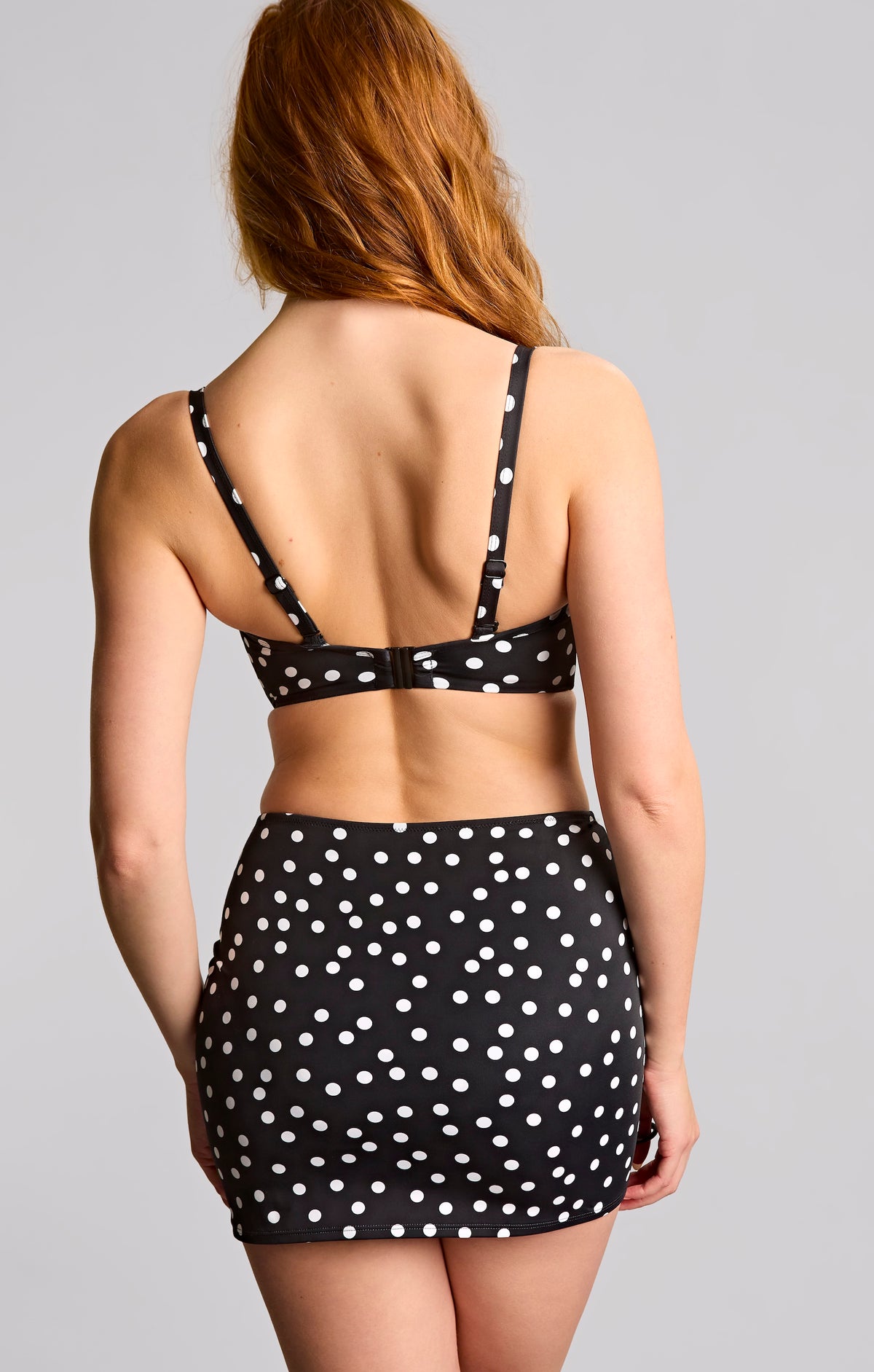 Woman wearing a black polka dot bikini set on a gray background