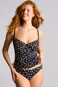 Woman wearing a black polka dot swimsuit on a gray background