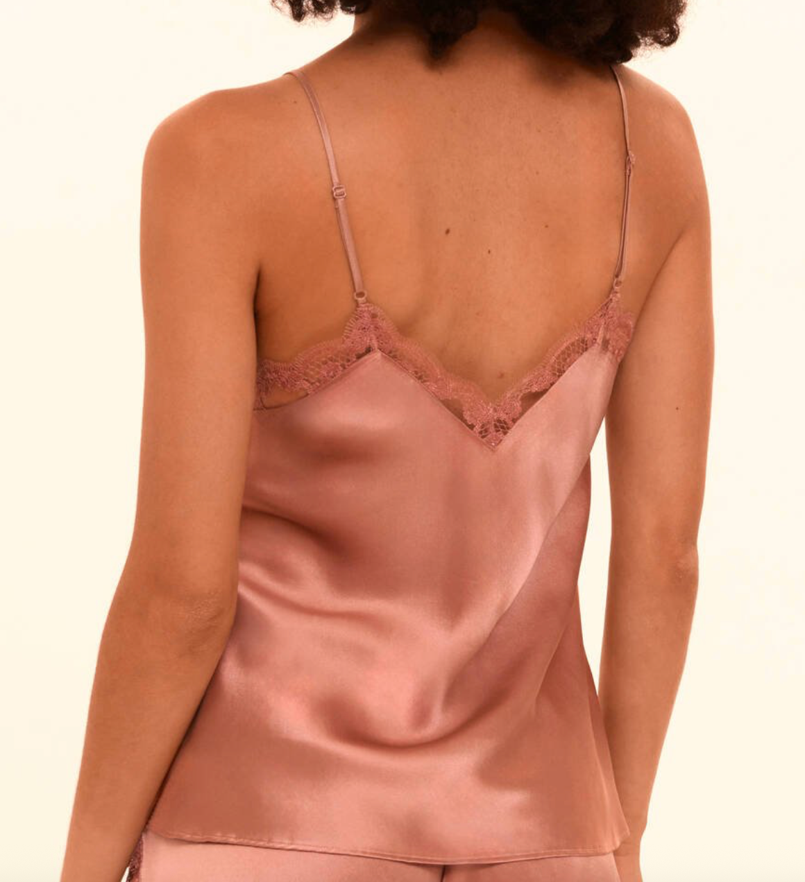 Pink silk camisole with lace trim on a plain background