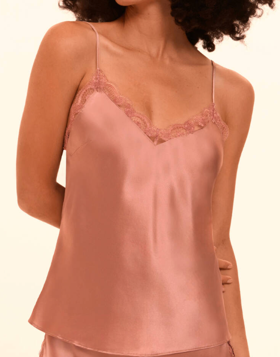 Pink silk camisole with lace trim worn by a model on a beige background
