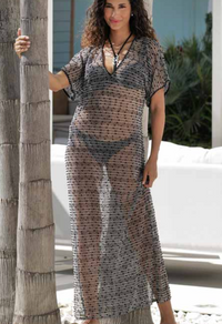 Woman wearing a sheer black and white patterned dress by a palm tree