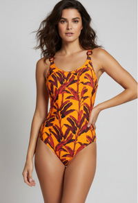 Woman wearing an orange and red leaf-patterned swimsuit on a plain background