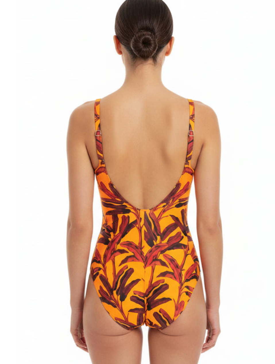 Woman wearing a one-piece swimsuit with a leaf pattern on a white background