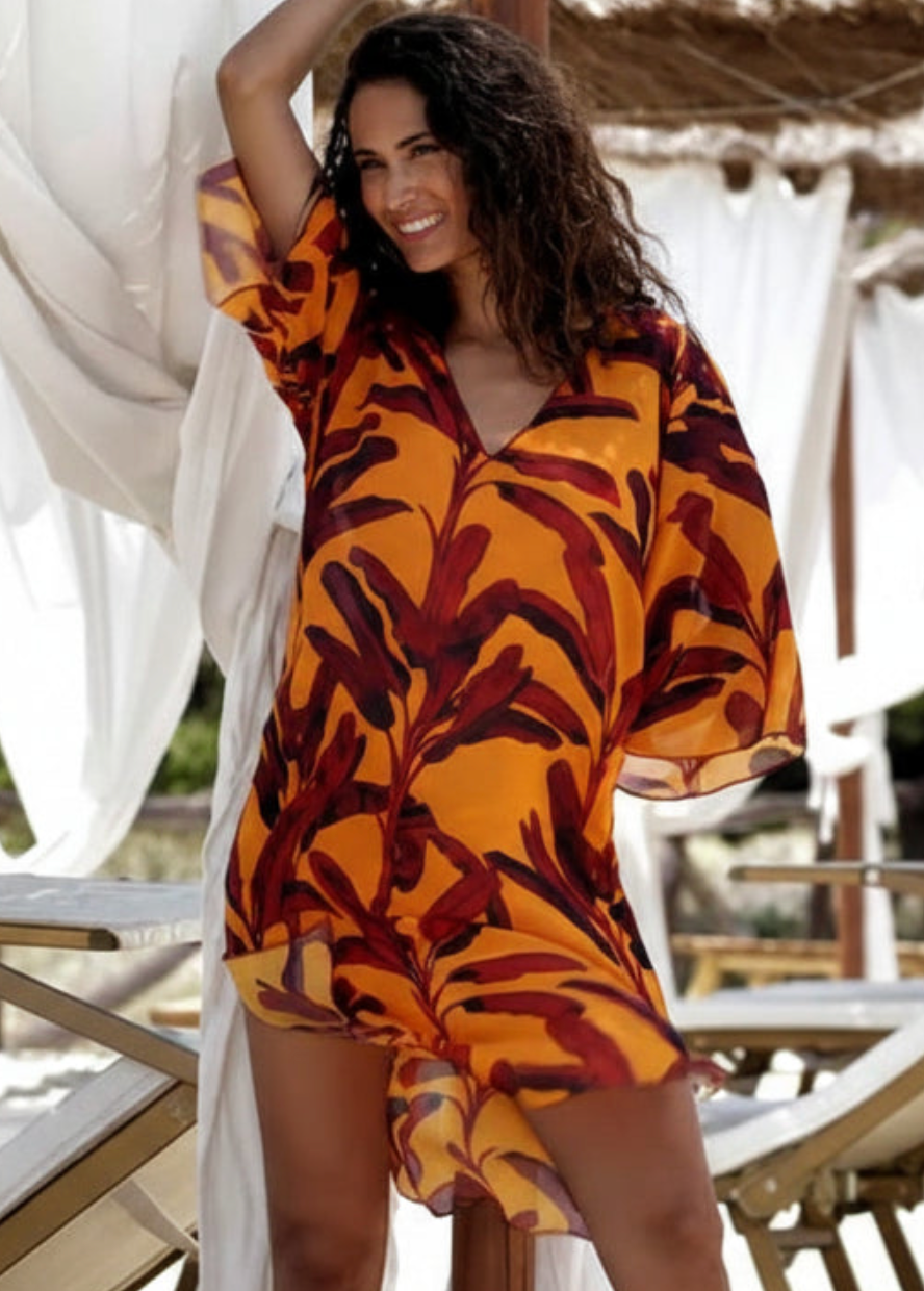 Woman wearing a patterned dress standing outdoors with white curtains in the background