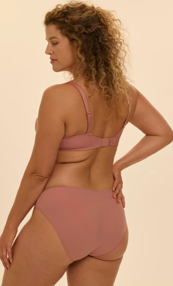 Woman wearing a two-piece swimsuit in a neutral color on a beige background