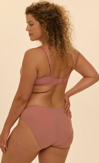 Woman wearing a two-piece swimsuit in a neutral color on a beige background