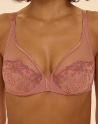 Pink bra with lace detailing on a beige background