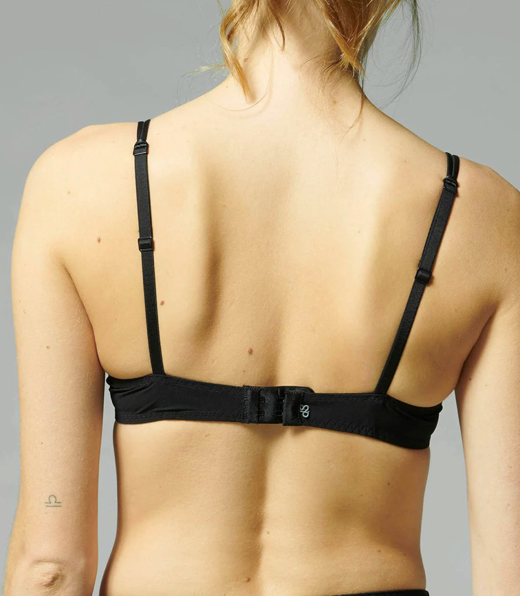 Black bra worn by a person on a gray background