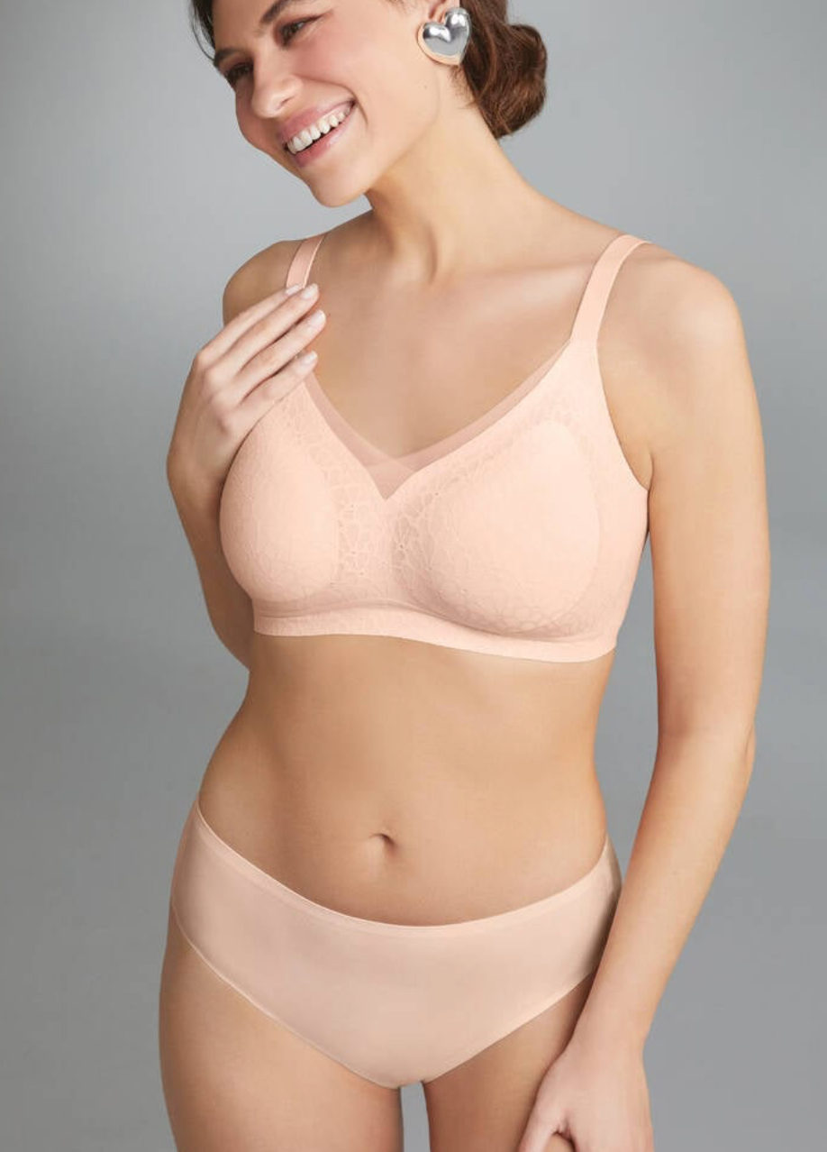 Woman wearing a beige bra and panties set against a gray background