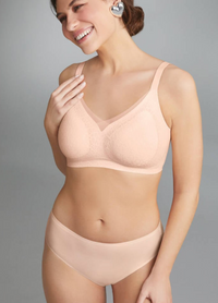 Woman wearing a beige bra and panties set against a gray background