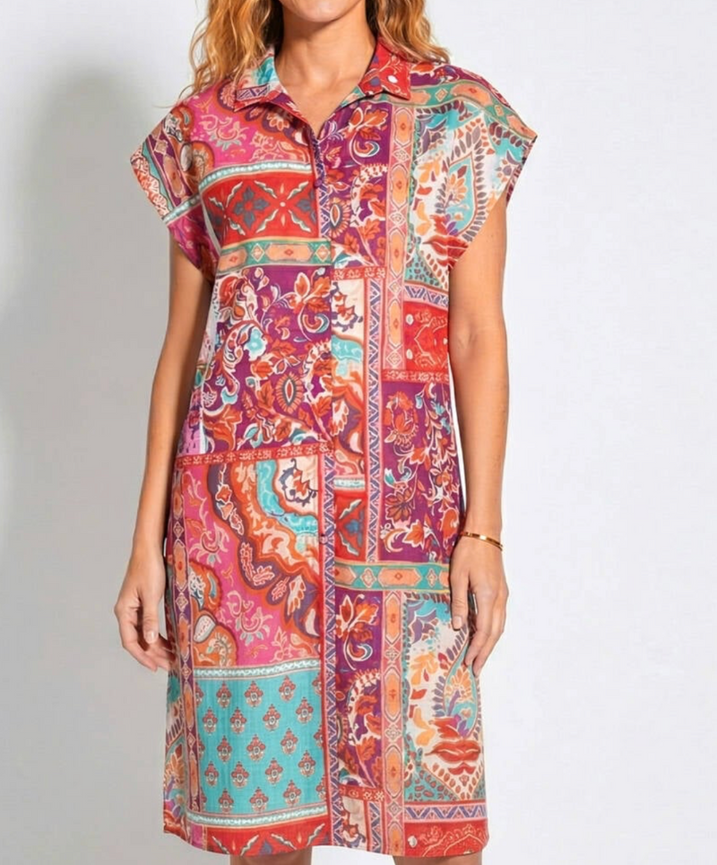 Woman wearing a colorful patterned dress on a plain background