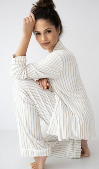 Woman wearing a white and gray striped outfit on a plain background