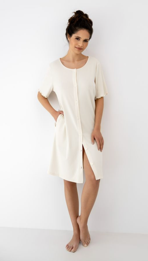 Woman wearing a soft beige night dress with a slit on a white background