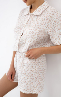 Person wearing a white floral dress against a plain background