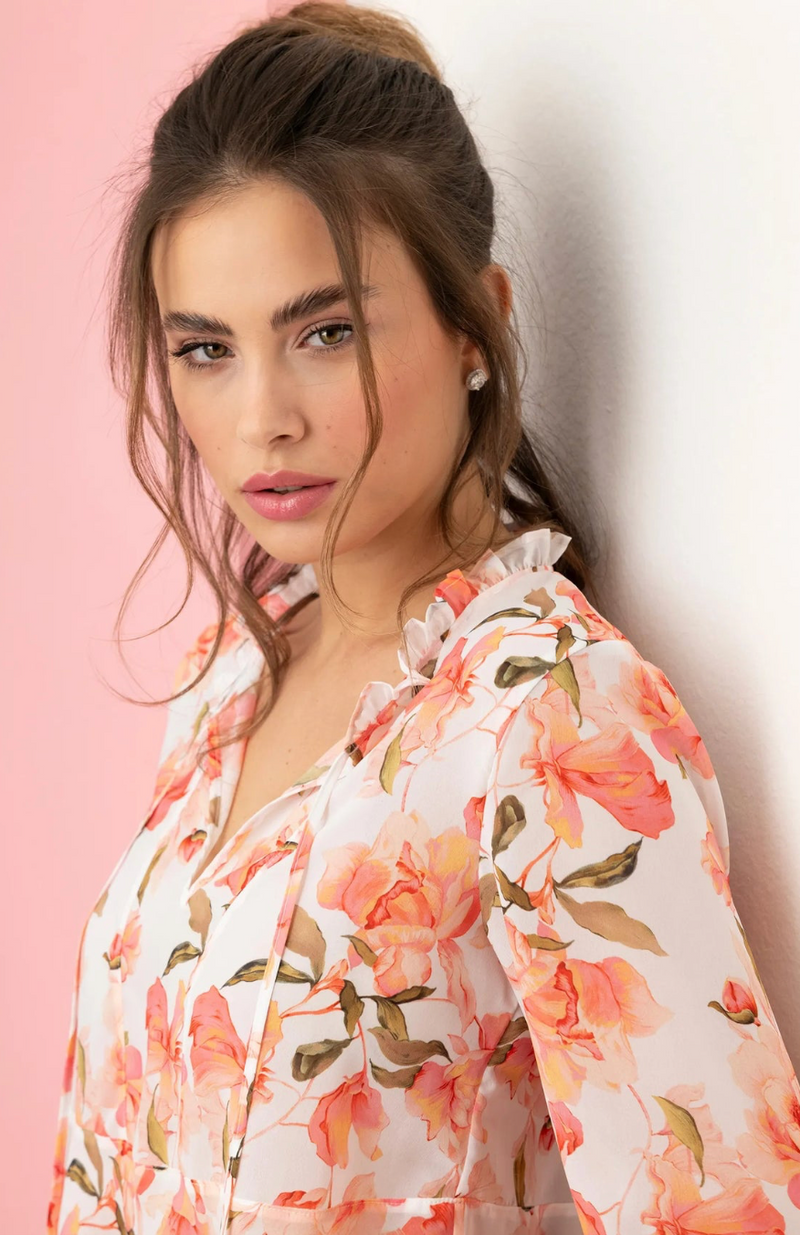Woman wearing a floral blouse against a pink background