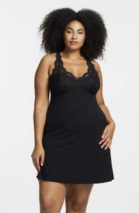 Woman wearing a black lace-trimmed nightgown against a white background