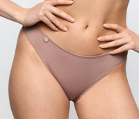 A close-up of a model wearing a low-rise, high-cut bikini bottom in a muted taupe-brown color. The fabric is smooth and solid, with a small metallic button detail on the left hip.