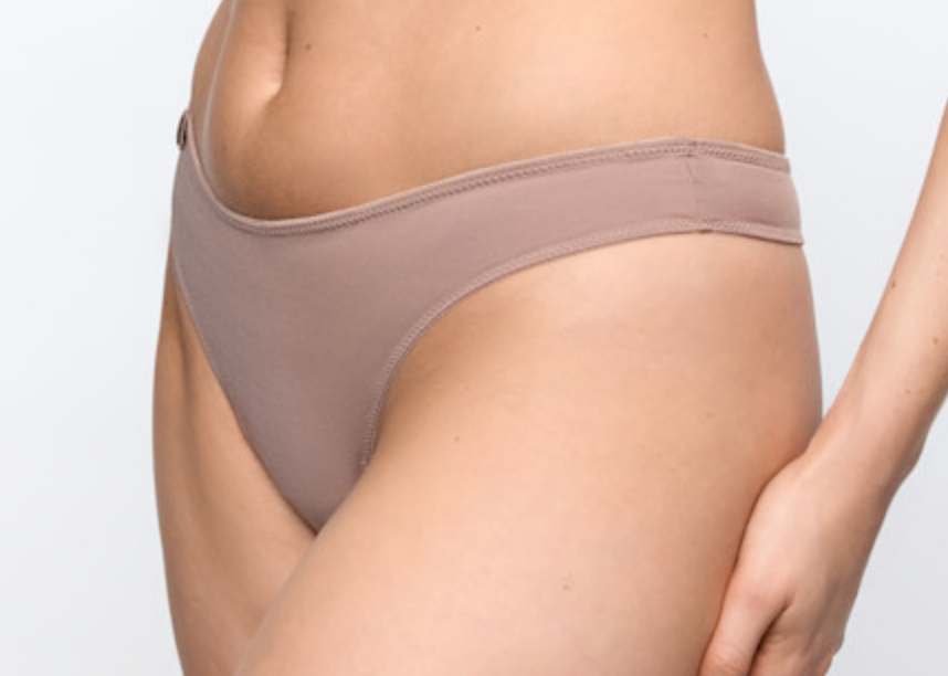 Close-up of a model wearing a low-rise, high-cut bikini bottom in a muted taupe color against a plain white background.