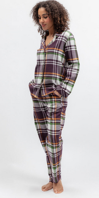 A woman modeling a two-piece long-sleeve pajama set with a plaid pattern in purple, green, orange, and white, standing against a plain white studio background.