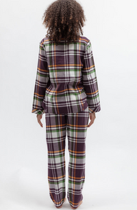 A model viewed from the back wearing a matching plaid pajama set with a long-sleeve top and pants in purple, green, orange, and white.