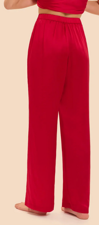 A person shown from the back wearing bright red high-waisted, wide-leg pants against a plain beige studio background.