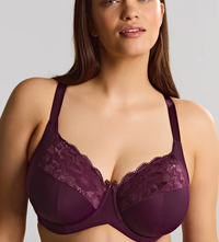 A woman wearing a deep plum purple lace and mesh underwire bra, shown from the chest up against a plain light gray studio background.