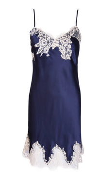 A navy blue silk slip dress with white lace trim along the neckline and hem, displayed against a solid white background.