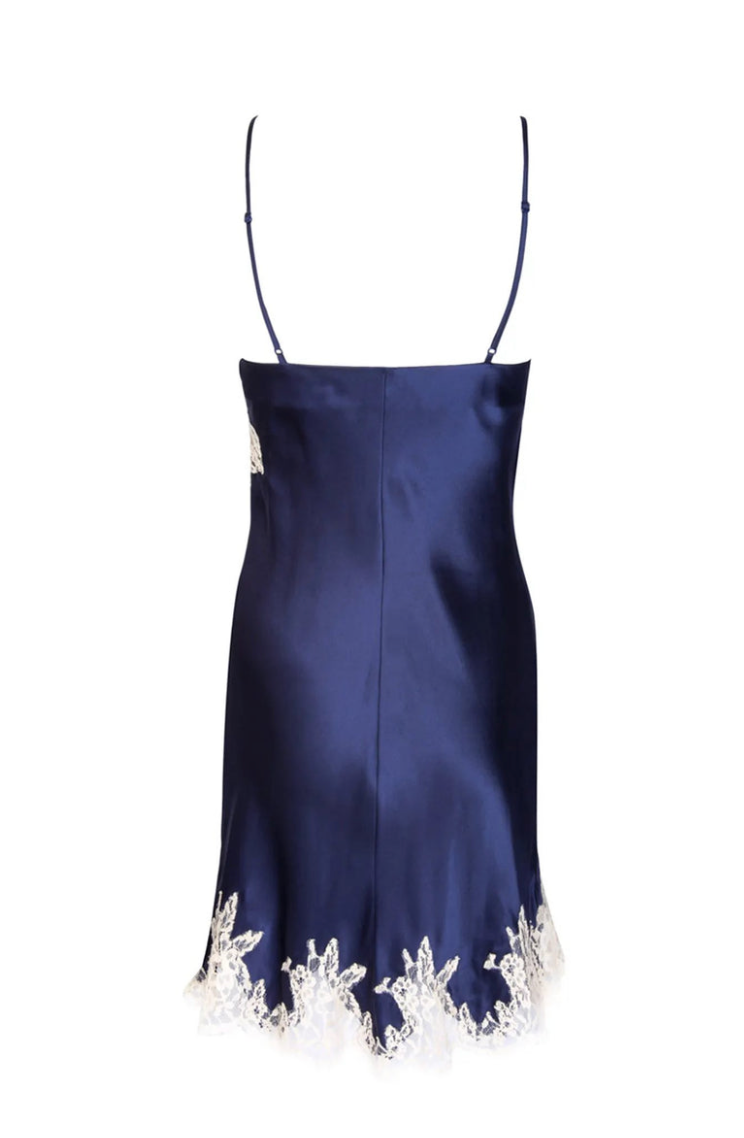 A navy blue silk slip dress with thin spaghetti straps and white lace trim along the hem, shown against a plain white background.
