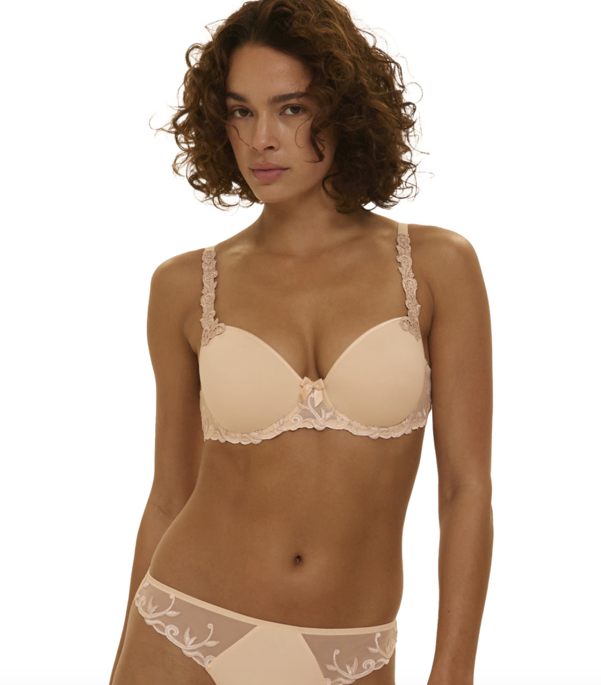 Woman wearing a beige bra and panties set on a white background