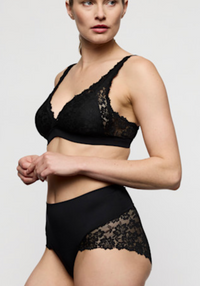 A model wearing a black lace bralette and matching high-waisted black lace-trim briefs against a light gray studio background.