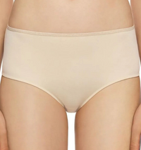 A close-up of a model wearing high-waisted, seamless underwear in a light beige or nude color, shown from the waist to the upper thighs against a plain white background.
