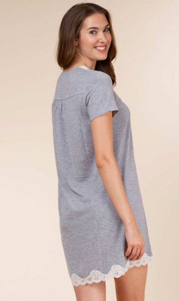 A woman wearing a heather gray short-sleeve nightgown with white lace trim at the hem, photographed against a plain beige studio background.