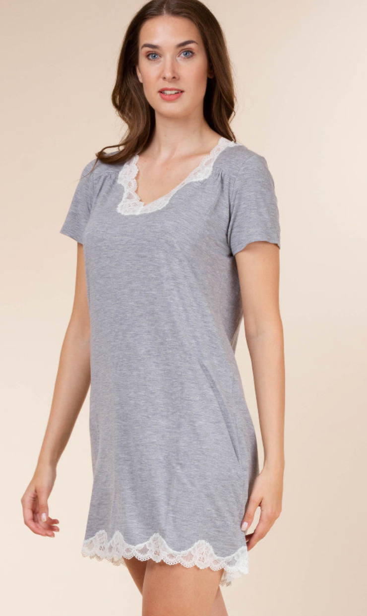 A woman wearing a heather gray short-sleeve nightgown with white lace trim at the hem, photographed against a plain beige studio background.
