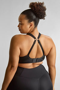 Woman wearing a black sports bra and leggings on a light gray background