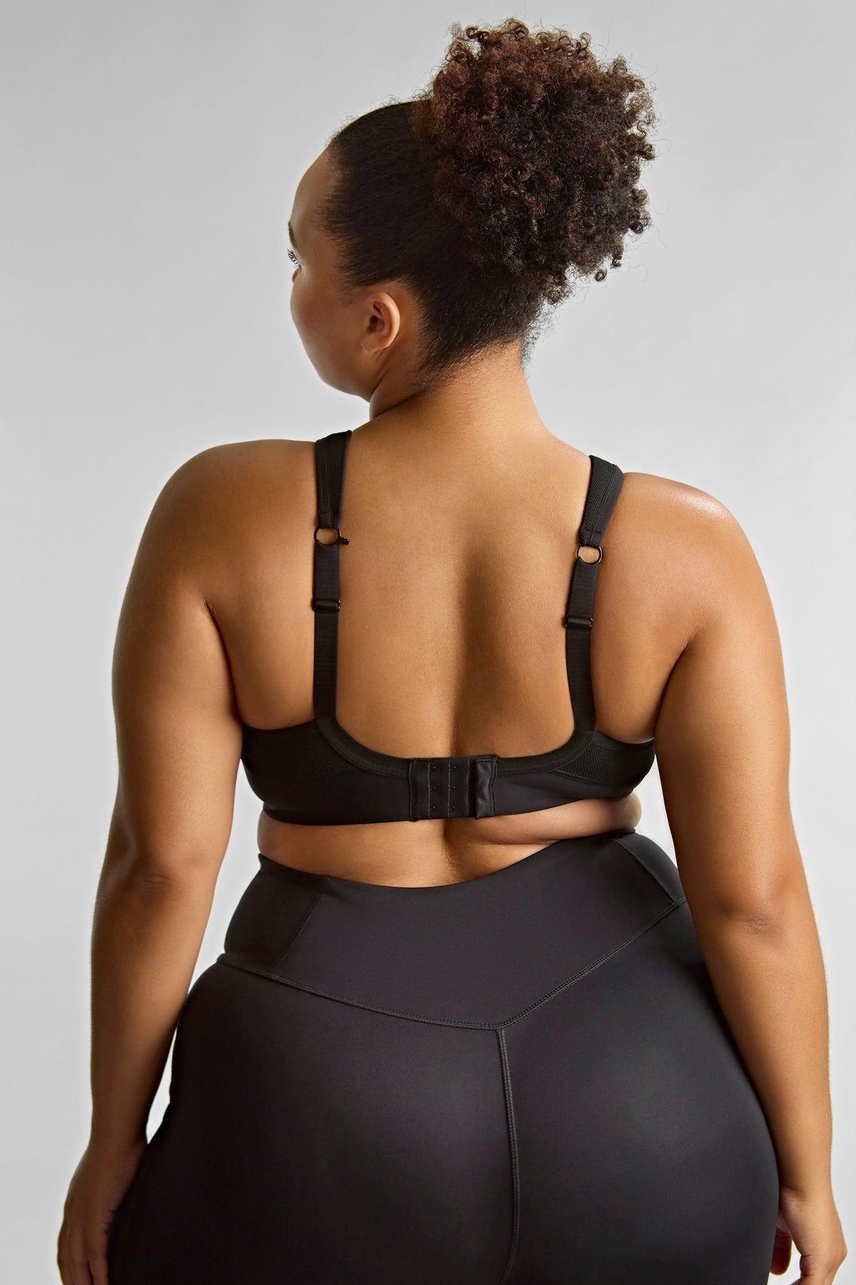Person wearing a black sports bra and leggings on a light gray background