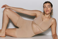 Woman wearing a beige shapewear garment against a plain background