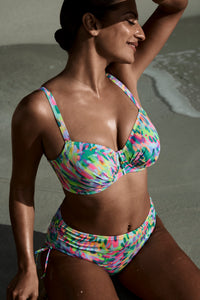 Woman wearing a colorful bikini sitting on sand