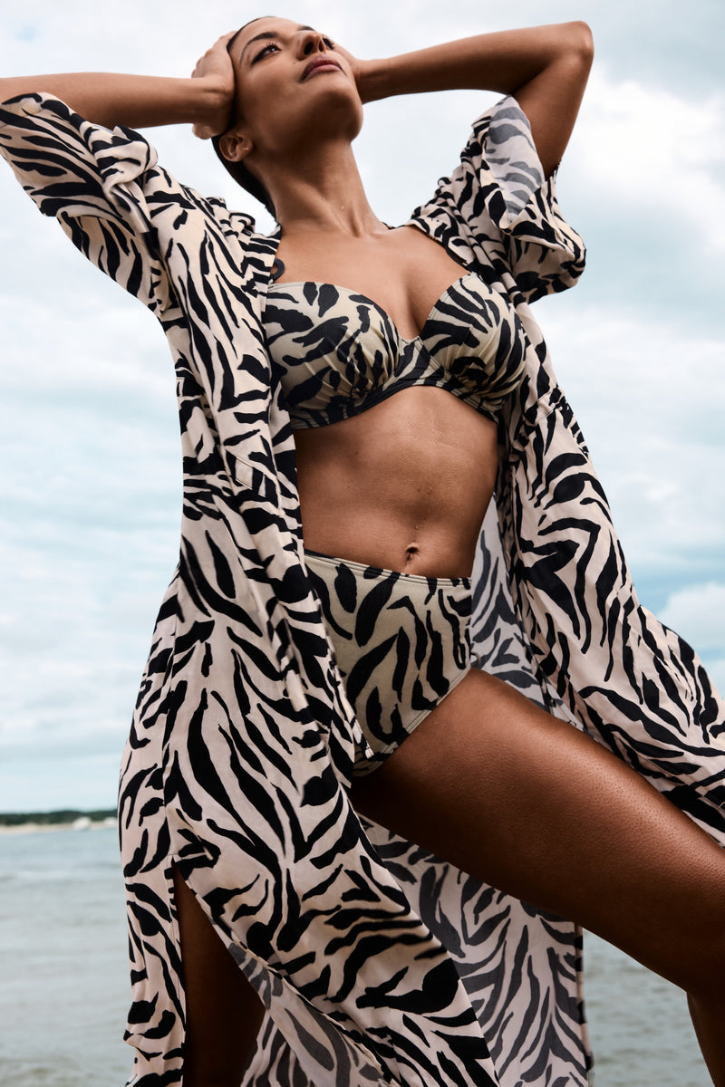 Woman in a zebra print cover-up and bikini standing by water
