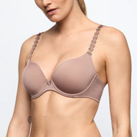 Woman wearing a beige bra with decorative straps on a white background