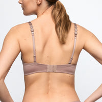Woman wearing a light brown bra against a plain background