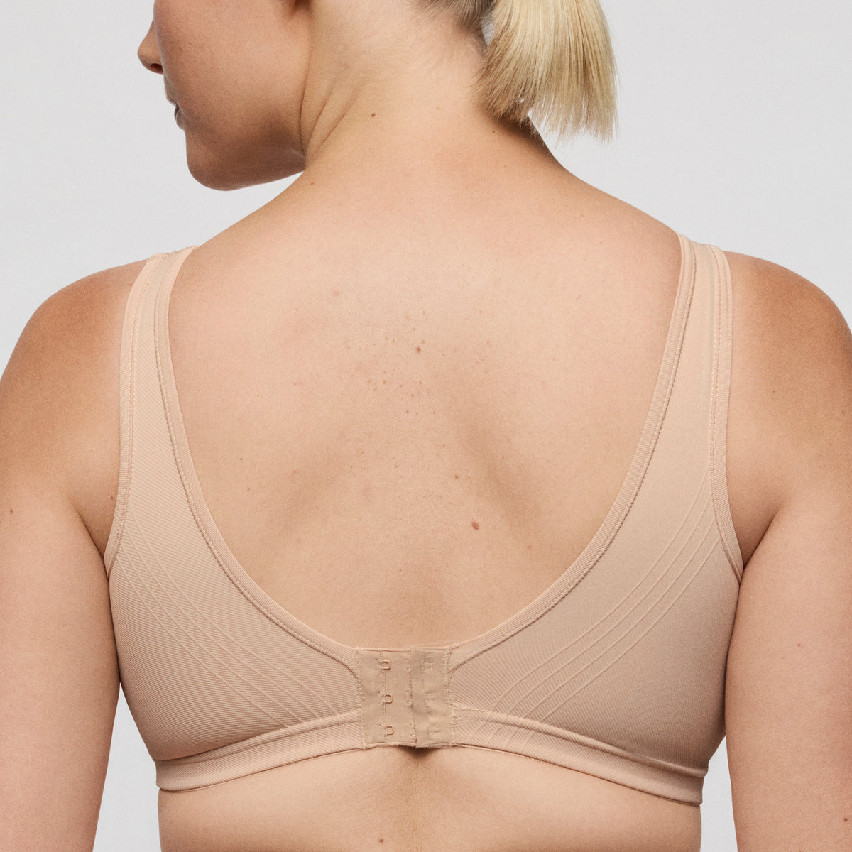 Beige wireless bra worn by a person on a plain background