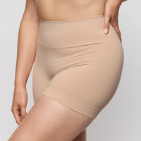 Beige shapewear being worn on a plain background