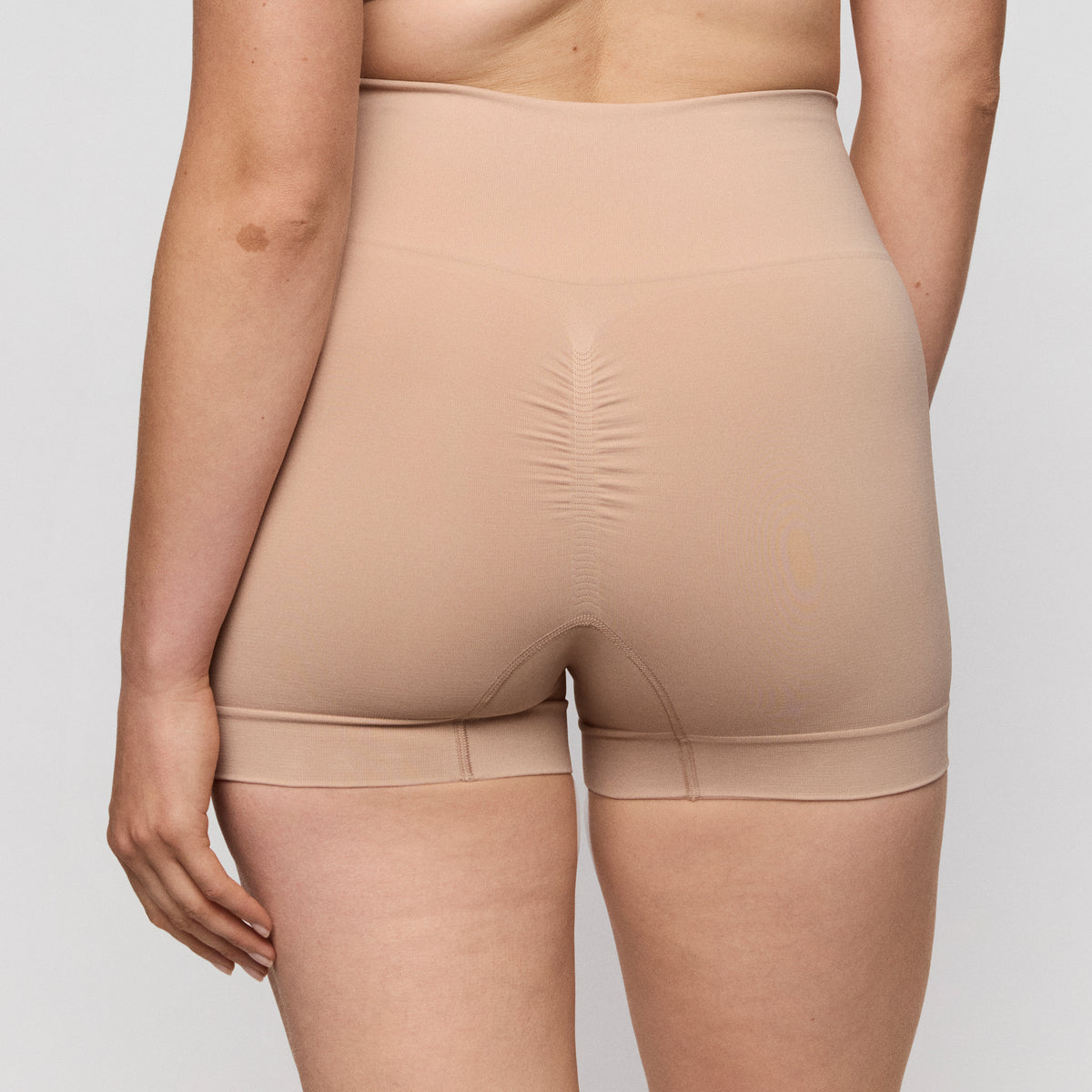 Beige shapewear worn by a person on a plain background