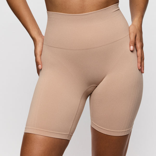 Beige high-waisted shorts worn by a person on a light gray background
